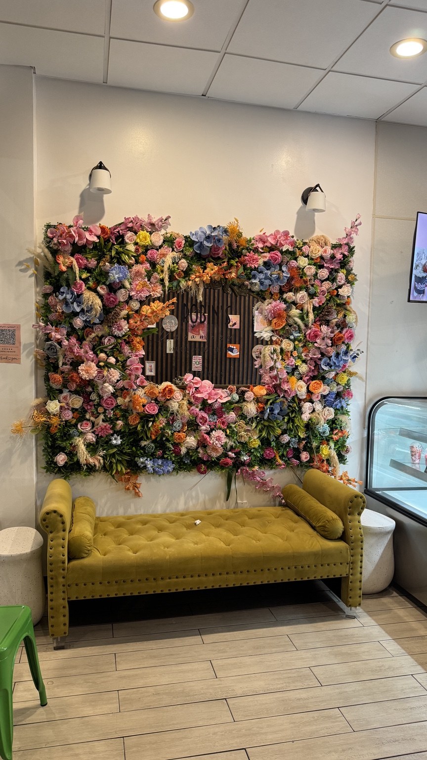 The flower wall and green sofa at Robin’s Creamery